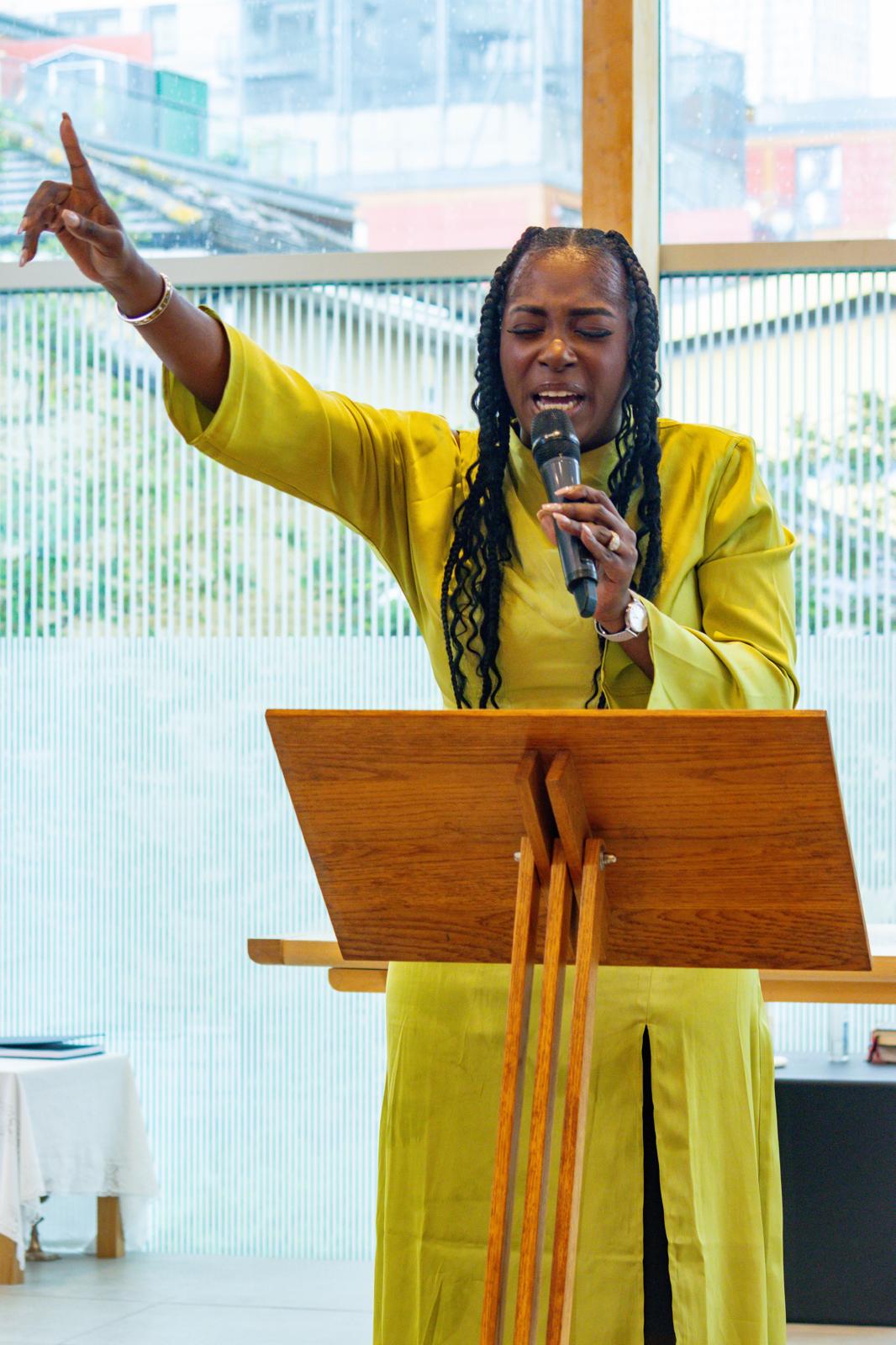 Pastor Nikki Okedele speaking in yellow outfit